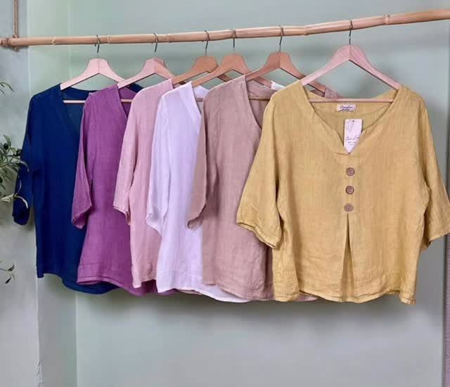 Linen blouses in navy, orchid, blush, white, sand and marigold on a bamboo rail